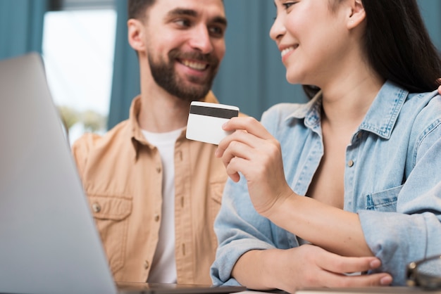 Feliz pareja de compras en línea usando laptop y tarjeta de crédito