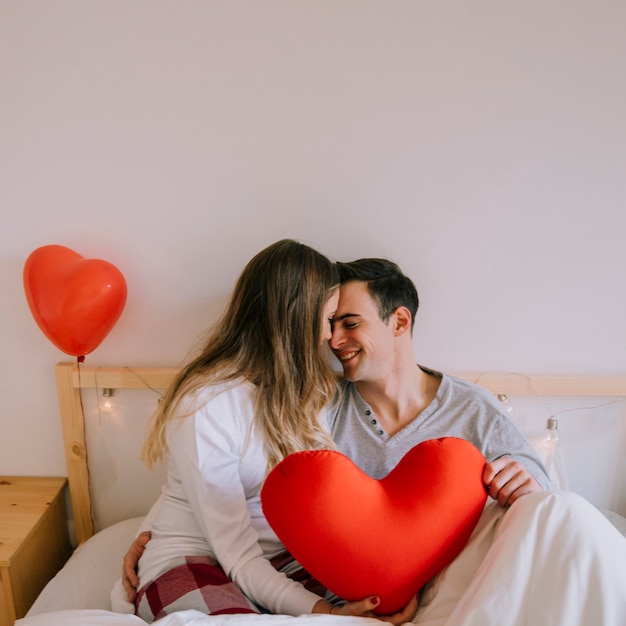 Feliz pareja con corazón en la cama