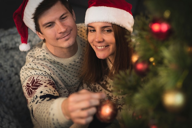 Feliz pareja decorando el árbol de navidad