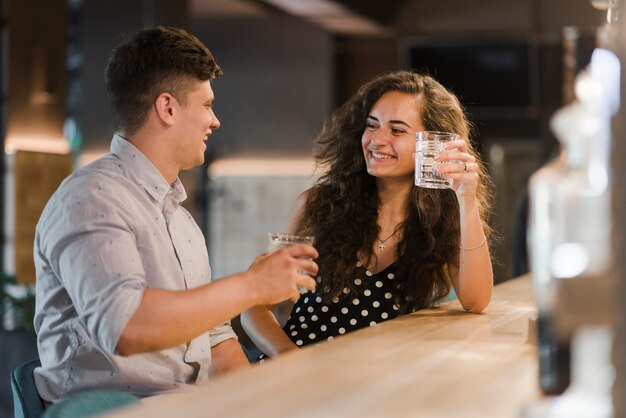 Feliz pareja disfrutando de bebidas en el bar