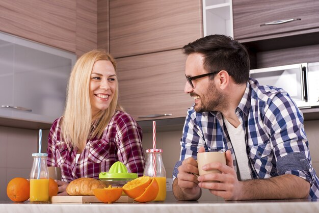 Feliz pareja disfrutando de su desayuno con jugo de naranja recién exprimido en la cocina