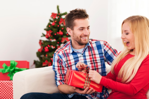 Feliz pareja divertirse durante la inauguración del regalo de Navidad