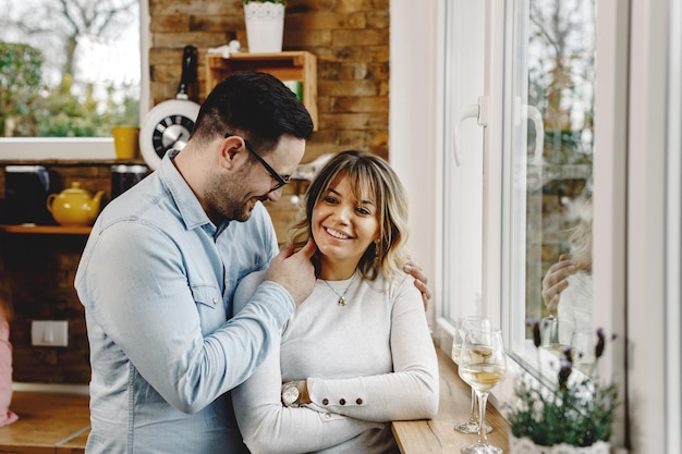 Foto gratuita feliz pareja enamorada parada junto a la ventana y comunicándose en la cocina