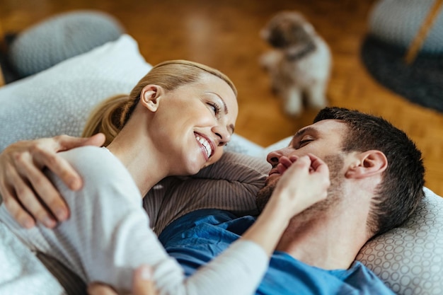 Feliz pareja enamorada relajándose en la cama y comunicándose