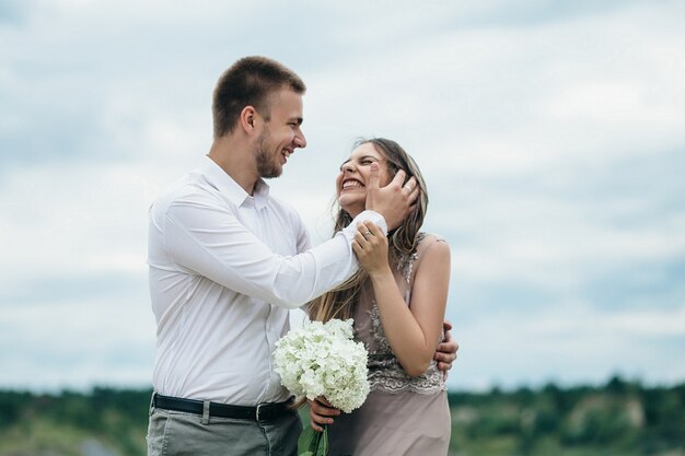 La feliz pareja de enamorados abrazándose cerca del río