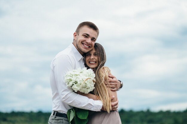 La feliz pareja de enamorados abrazándose cerca del río