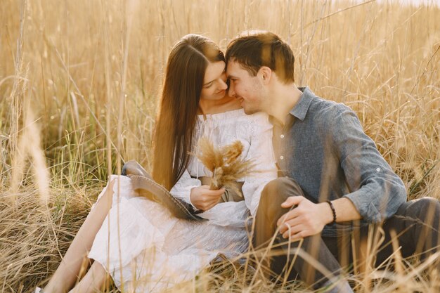 Feliz pareja de enamorados en el campo de trigo al atardecer