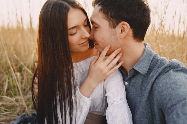 Feliz pareja de enamorados en el campo de trigo al atardecer