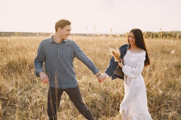 Feliz pareja de enamorados en el campo de trigo al atardecer