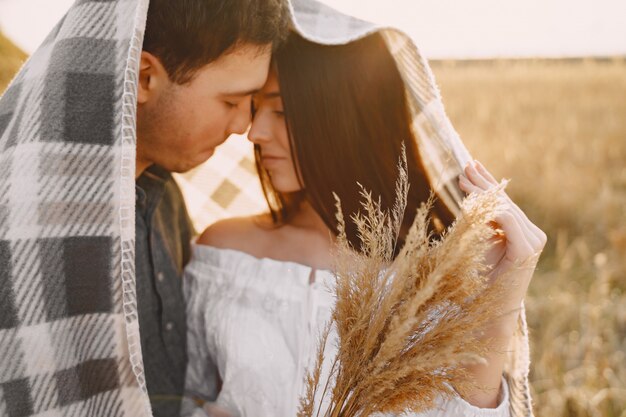 Feliz pareja de enamorados en el campo de trigo al atardecer
