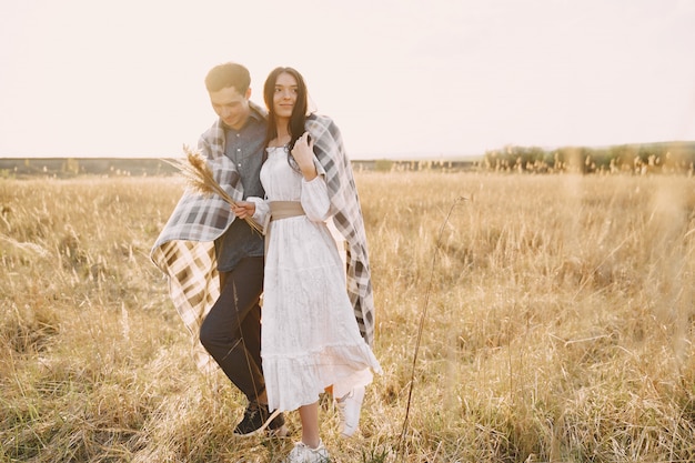 Feliz pareja de enamorados en el campo de trigo al atardecer