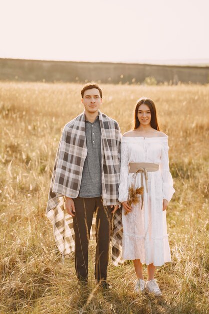 Feliz pareja de enamorados en el campo de trigo al atardecer