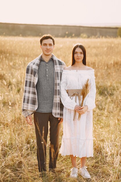 Feliz pareja de enamorados en el campo de trigo al atardecer