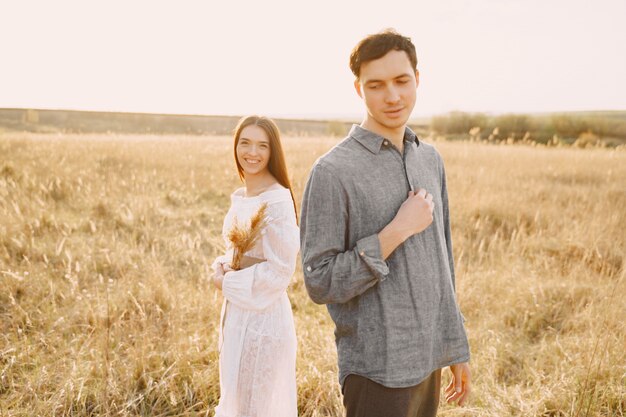 Feliz pareja de enamorados en el campo de trigo al atardecer