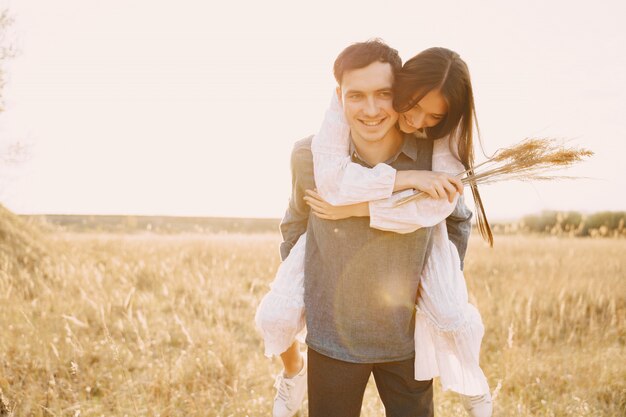 Feliz pareja de enamorados en el campo de trigo al atardecer