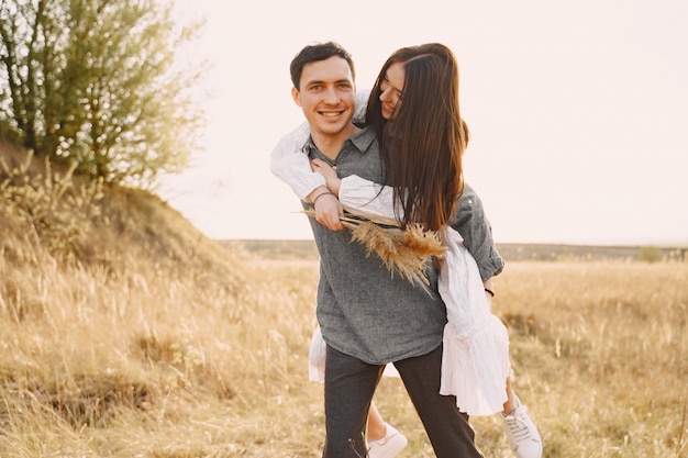 Feliz pareja de enamorados en el campo de trigo al atardecer