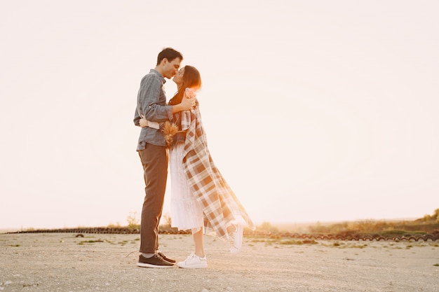 Feliz pareja de enamorados de pie en la calle al atardecer