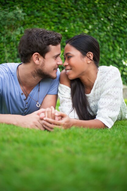 Feliz pareja étnica joven descansando sobre la hierba