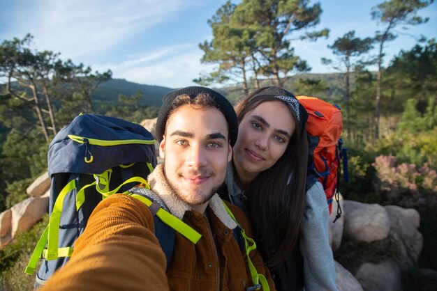 Feliz pareja de excursionistas tomando selfie. Hombre y mujer con ropa informal y mochilas mirando a la cámara. Amor, ocio, concepto de tecnología.