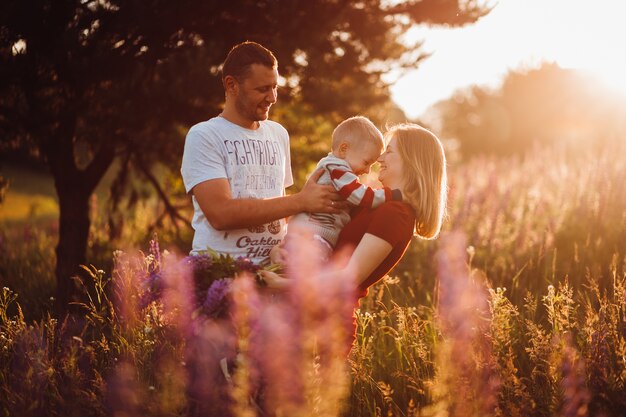 Feliz pareja de familia con hijo pequeño posan en el campo de lavanda