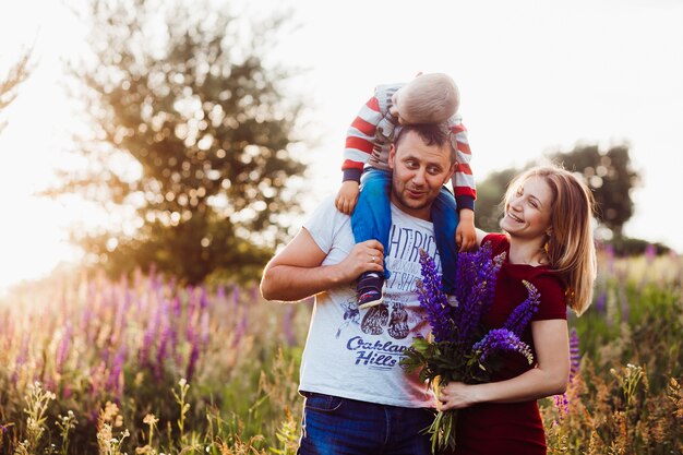 Feliz pareja de familia con hijo pequeño posan en el campo de lavanda