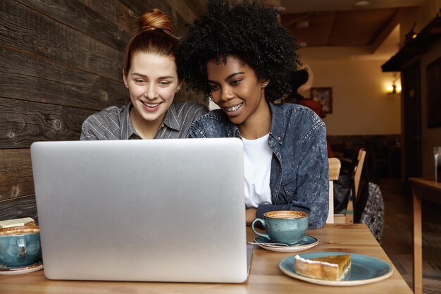 Feliz pareja femenina del mismo sexo usando el portátil en el café