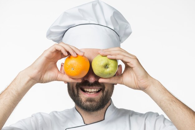 Feliz pareja con frutas maduras delante de su ojo sobre fondo blanco
