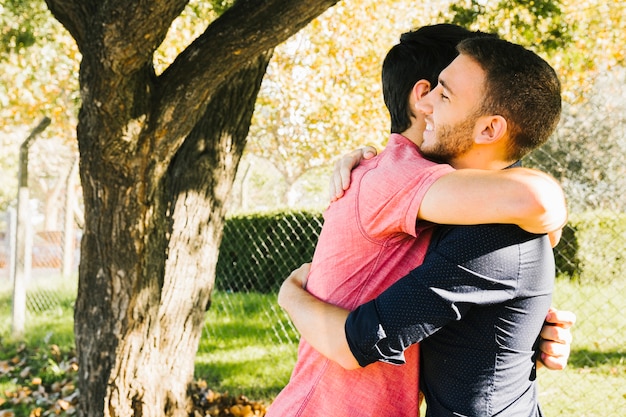 Feliz pareja gay abrazando en el parque