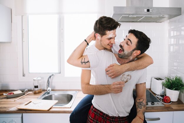Feliz pareja gay divirtiéndose en la cocina
