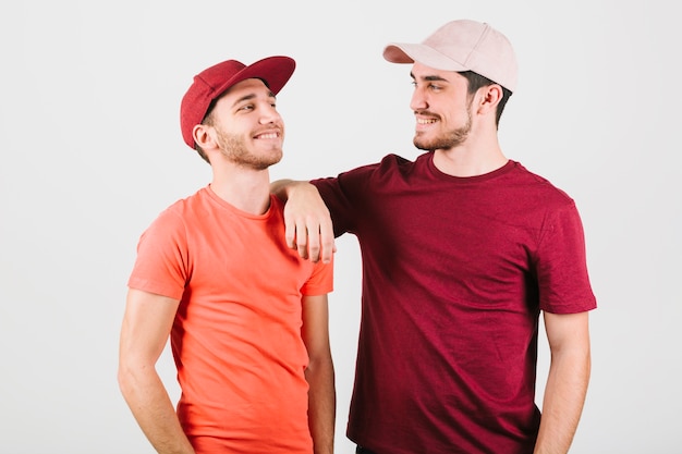 Feliz pareja gay en gorras de pie cerca