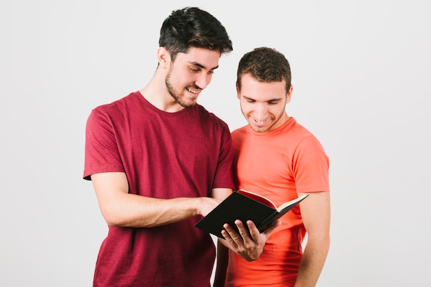 Feliz pareja gay mirando atentamente en el bloc de notas