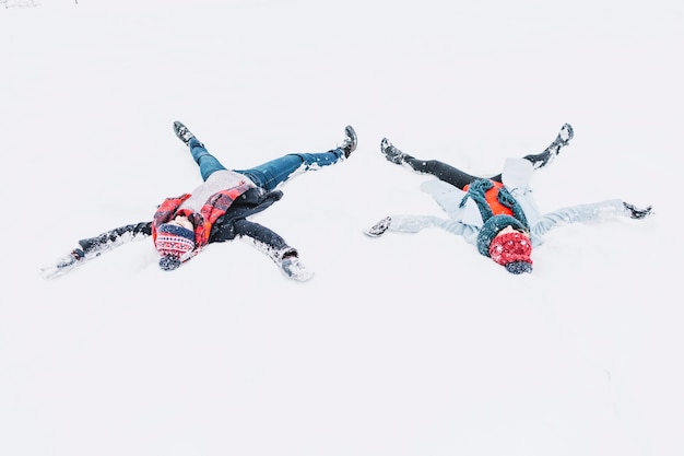 Feliz pareja haciendo ángeles en la nieve