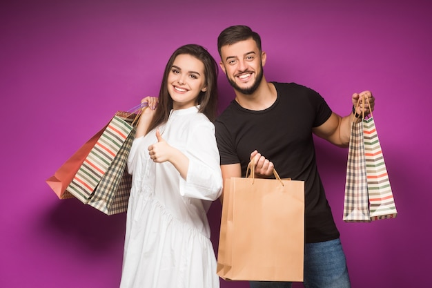 Feliz pareja hermosa posando con bolsas de la compra en violeta