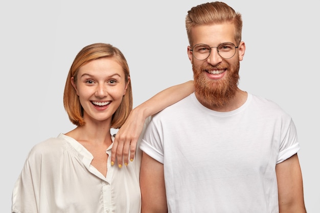 Feliz pareja de hombre y mujer vestidos con ropa blanca casual, tienen expresiones positivas