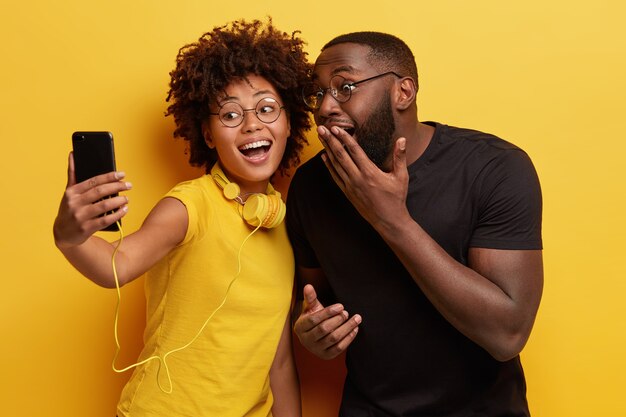 Feliz pareja de hombres y mujeres de piel oscura se divierten juntos, posan para hacer un retrato selfie