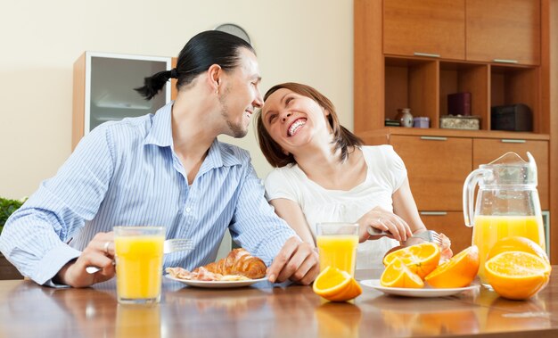 Feliz pareja con huevos revueltos con tocino en la mañana