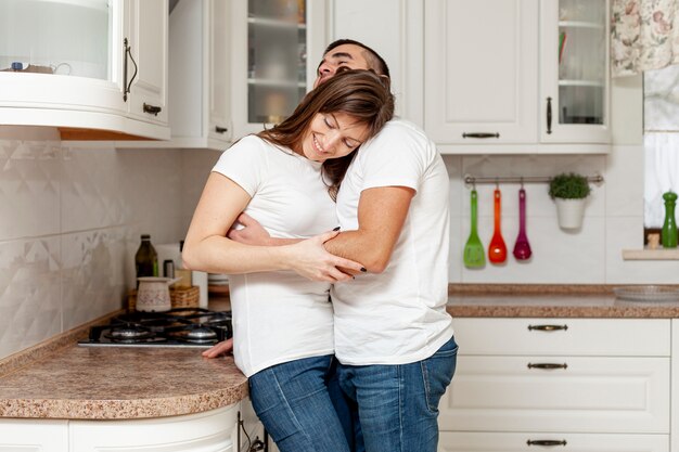 Feliz pareja joven abrazando en cocina