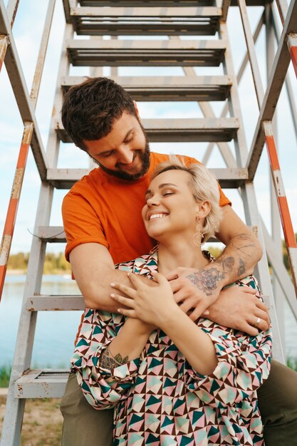 Feliz pareja joven abrazándose y riendo al aire libre en las escaleras