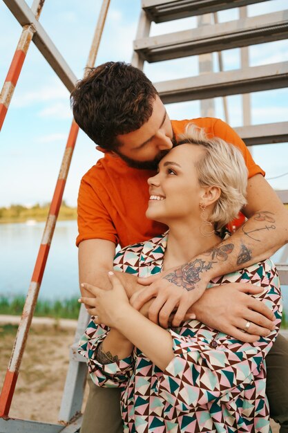 Feliz pareja joven abrazándose y riendo al aire libre en las escaleras