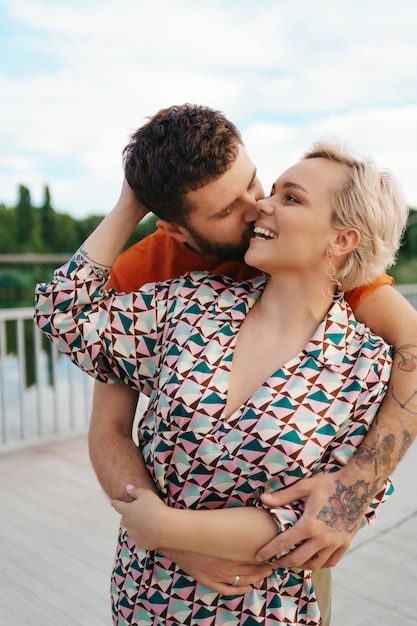 Feliz pareja joven abrazándose y riendo al aire libre.