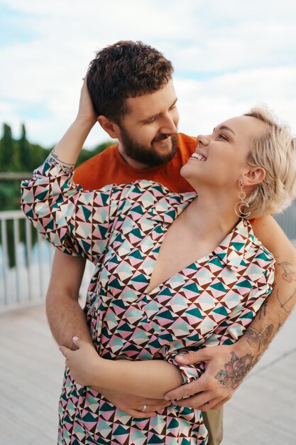 Feliz pareja joven abrazándose y riendo al aire libre.