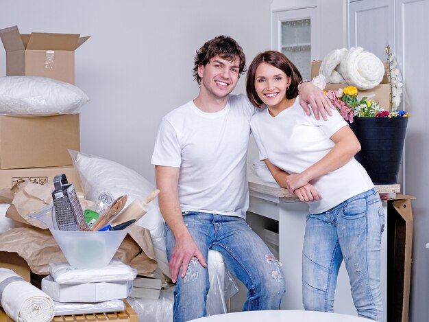 Feliz pareja joven alegre abrazando en el piso nuevo