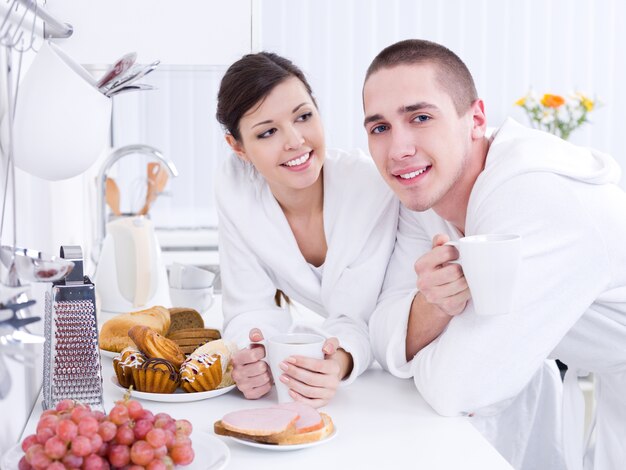 Feliz pareja joven amorosa desayunando juntos en la cocina