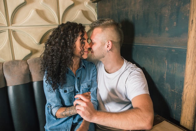 Feliz pareja joven está bebiendo café y sonriendo mientras está sentado en el café