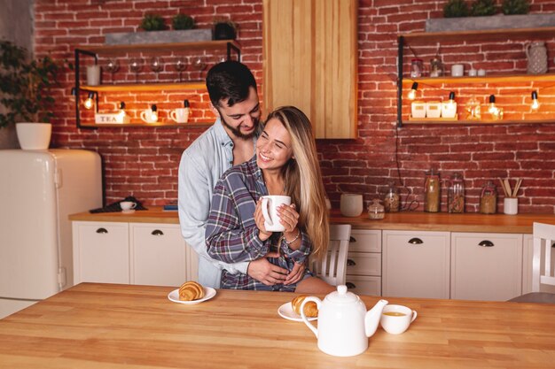 Feliz pareja joven bebiendo té en la cocina