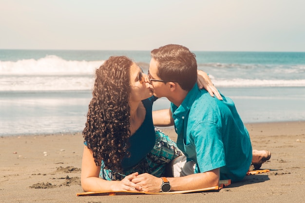 Feliz pareja joven besándose en la playa tropical