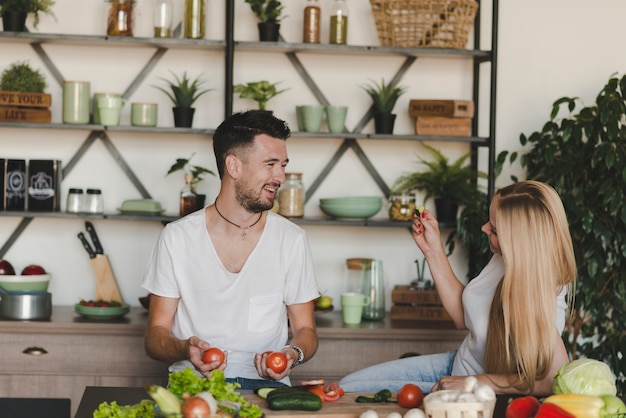 Foto gratuita feliz pareja joven burlarse en la cocina