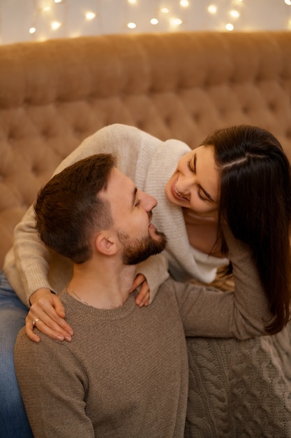 Feliz pareja joven casada abrazándose, sentados juntos en el acogedor sofá