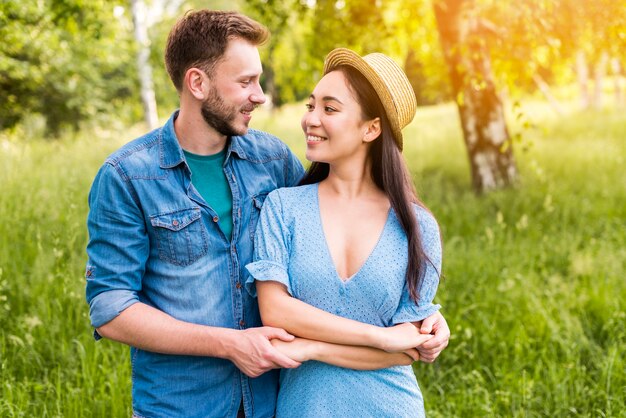 Feliz pareja joven cogidos de la mano y sonriendo en la naturaleza