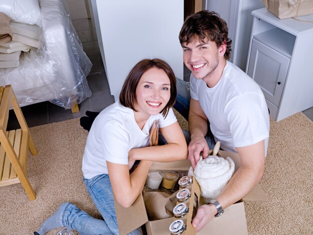 Feliz pareja joven desembalar sus cosas después de mudarse